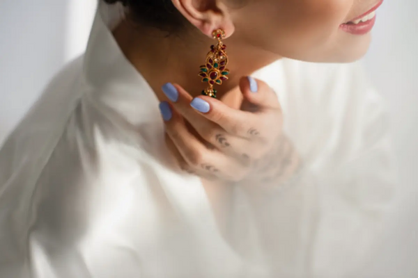 The woman wears beautifully cut-out earrings