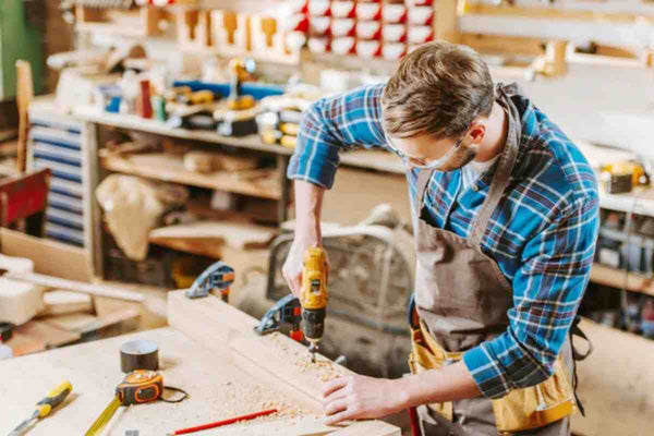 Workers carve wooden strips with a drilling machine.