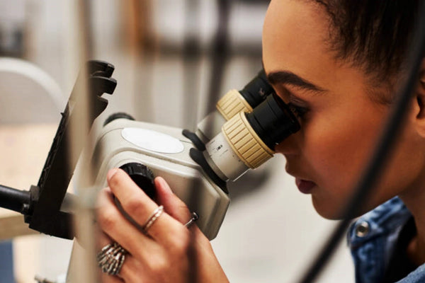 talented woman focuses intently examining sparkling jewels using microscope her